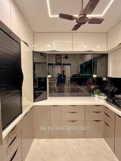 This U-shaped kitchen design maximizes counter space and storage. The glossy cabinets and reflective backsplash make the room feel bright and spacious.
