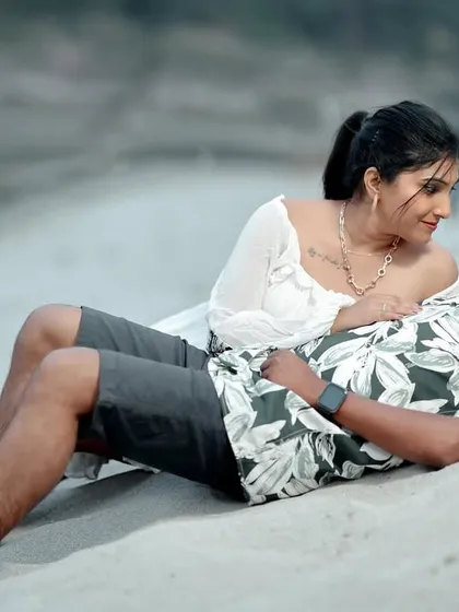 A relaxed and loving moment on the sand, capturing the easy comfort between the couple. The focus is entirely on their connection.