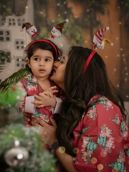 A mother gives her child a sweet kiss on the cheek amidst the festive decor. These are the tender moments that make the holidays so special.