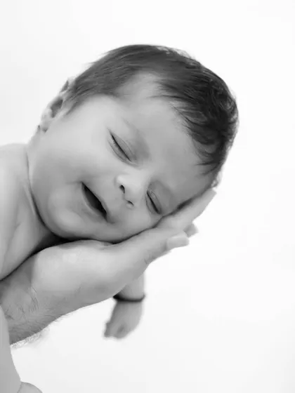 There is nothing more peaceful than a sleeping newborn. This simple, black and white portrait focuses on the baby's serene expression, held safely in a parent's hand, a memory of how tiny they once were.