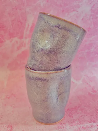 A pair of the light purple grip mugs, stacked. Their minimalist design and soothing color make them a peaceful addition to your daily routine.