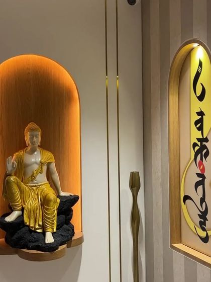 Another view of the spiritual entrance, where a Buddha statue is paired with a piece of calligraphy art. The warm, indirect lighting in the niche creates a soft, inviting glow, making this corner a focal point of peace.