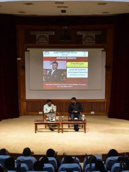 The stage setup at IIM Bangalore, with the event poster on the screen. The session was part of the Public Policy Club's speaker series.