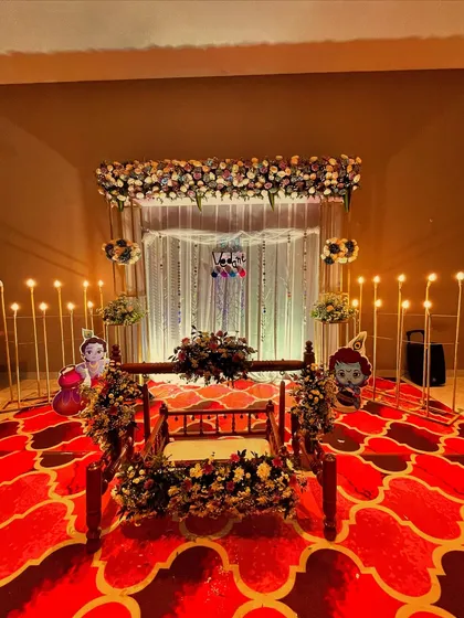 The same beautiful cradle ceremony setup, showcasing the vibrant red patterned carpet that adds richness to the decor.