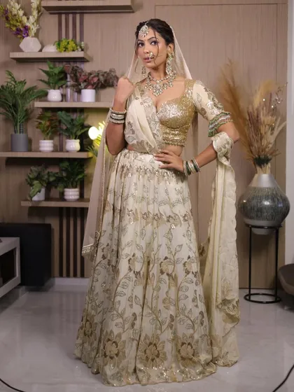 An elegant off-white and gold floral lehenga. This is a sophisticated choice for an engagement or day wedding, offering a classic look with a touch of sparkle.