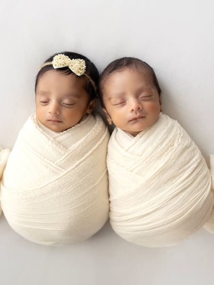 Two little peas in a pod! These twin girls are swaddled snugly in cream-colored wraps, looking so peaceful and perfect.