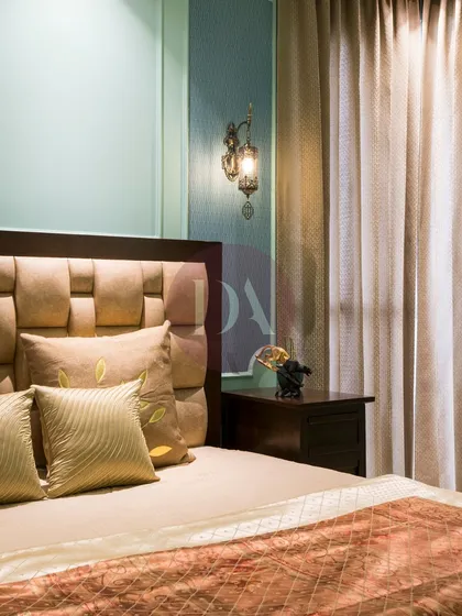 A detail shot of the bedside, highlighting the texture of the curtains and the classic design of the wall lamp. Every element is chosen to contribute to a feeling of serenity.
