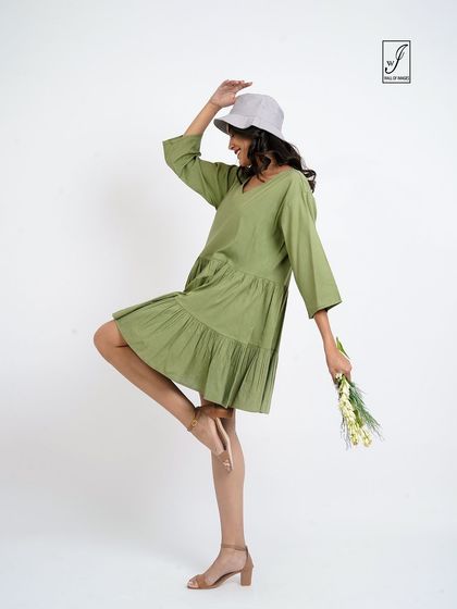 A fun and energetic pose in a tiered green dress, perfect for a summer or spring collection.