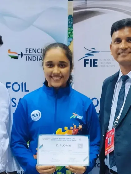 Two of our coaches flank a successful fencer holding her diploma at an FIE tournament. Our coaching team provides comprehensive support to help our athletes succeed at every level.