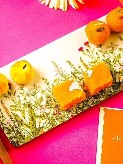 A beautiful rectangular platter with a botanical design, styled with Indian sweets for a festive look.
