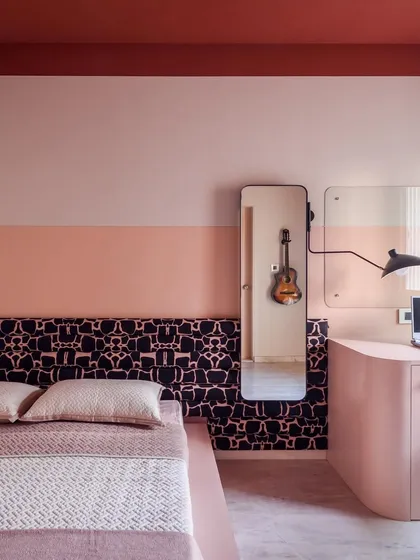 This room features a rich wine-red ceiling and two-tone pink walls, creating a warm and playful atmosphere. The custom headboard and minimalist furniture keep the space from feeling cluttered.