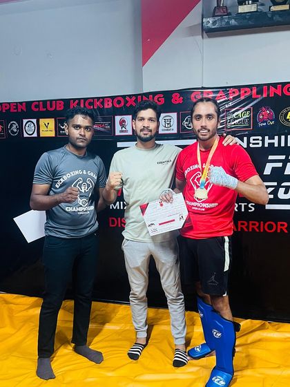 A student celebrates his first fight victory with his coaches. This is a huge milestone that is the result of months of dedicated training.