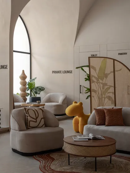 This view shows the interplay between the private lounge areas and the main space. A playful yellow seat adds a pop of color, while the arched window brings in natural light.
