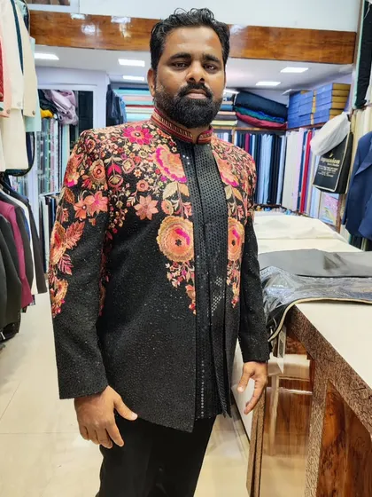 A client showcasing a stunning black Indo-Western jacket with vibrant, multi-colored floral embroidery. This is a bold and artistic piece for any celebration.
