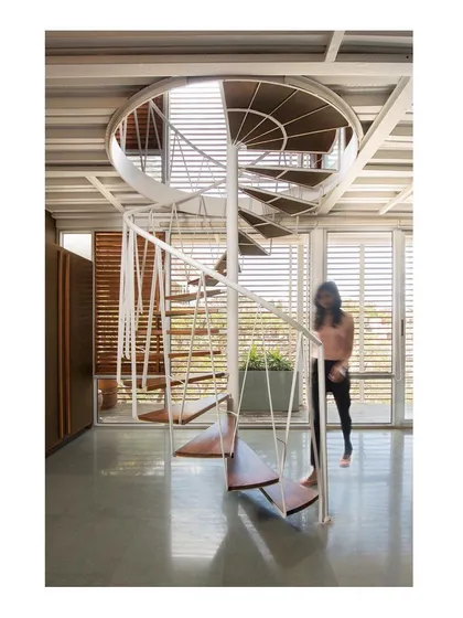 The spiral staircase is designed to be both functional and sculptural. Its delicate, woven steel structure allows light to pass through, making it feel lightweight and transparent within the open-plan studio.