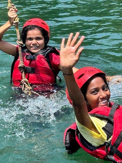 Two participants enjoy a rope swing activity in the water, a fun and thrilling part of our Dandeli camp.