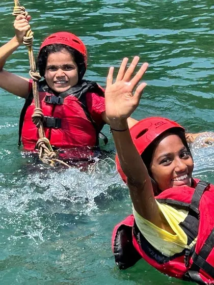 Two girls enjoy a rope swing activity in the water, another fun and challenging element of our Dandeli camp.