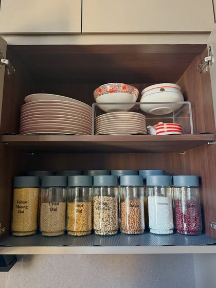 We maximize cabinet space by using shelf risers for plates and dedicating the lower shelf to neatly labeled jars of dals and grains. This creates two distinct, easy-to-access zones in one cabinet.
