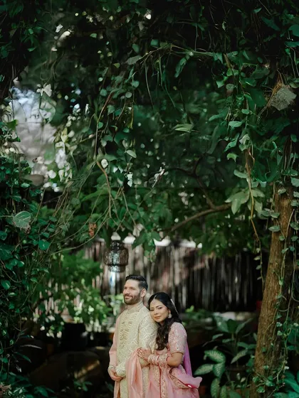 A serene portrait of a couple standing together under a canopy of lush green leaves. This image highlights a quiet, shared moment of peace and togetherness amidst the beauty of nature.