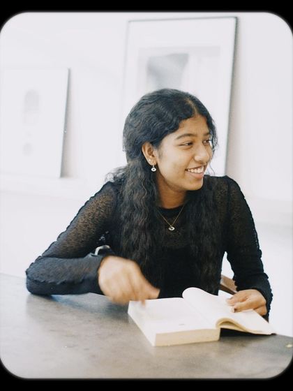 A student smiling as she looks up from her book. Our cafe is a happy place for studying and relaxing.
