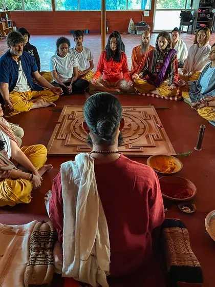 We gather in a circle around a sacred yantra for a ceremony. This practice of sitting together in silence and presence is a core part of the ashram experience, fostering a deep sense of unity.