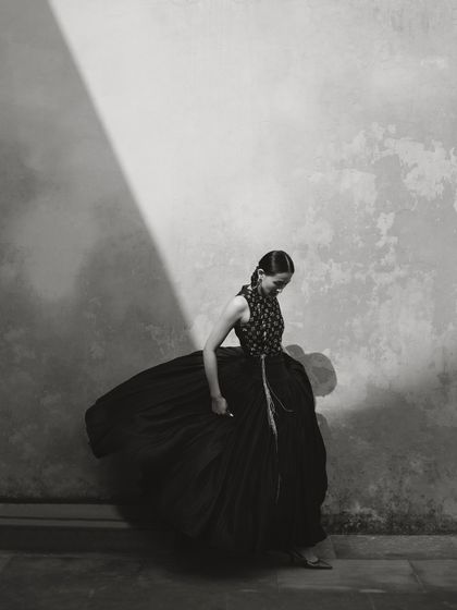 A black and white photo capturing the movement of a full skirt against a textured wall.