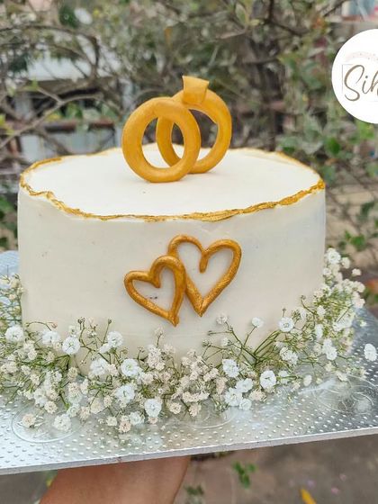 Gypsy dreams. A simple and elegant engagement cake featuring delicate baby's breath, gold hearts, and a fondant ring topper for a rustic and romantic feel.