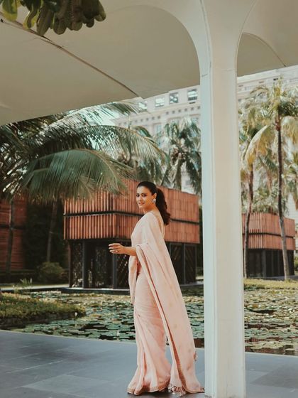 The full drape of the pink saree is visible as Kajol walks through a beautiful architectural space.