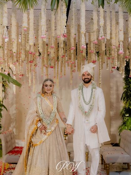 A stunning couple portrait under a ceiling of hanging floral strings. The all-white theme with subtle pops of color creates a look of modern, ethereal romance.