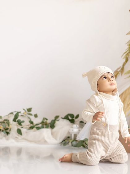 A happy baby in a minimalist, boho-inspired first birthday setup with a teepee.