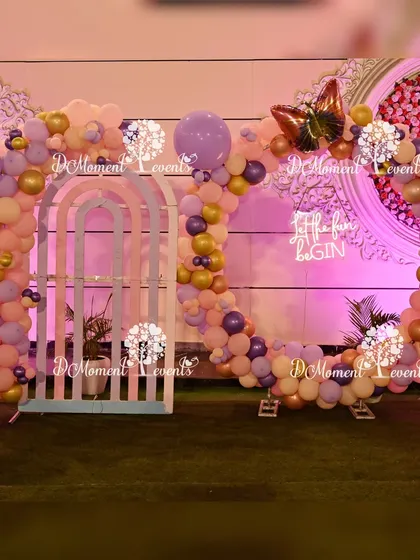 A unique circular photo frame made of pastel balloons with a butterfly foil balloon accent. This setup, placed on an artificial grass patch, provides a whimsical spot for pictures.