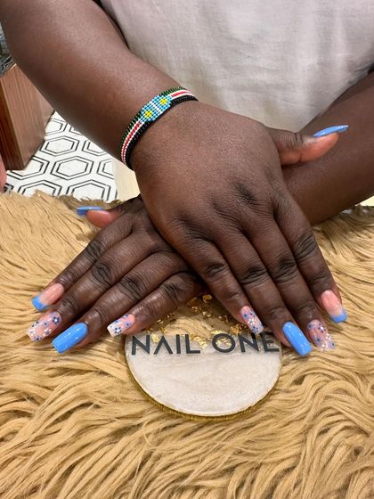 A beautiful and fresh take on the French manicure. This set features bright blue tips on square-shaped nails, with accent nails adorned with delicate floral art and glitter.