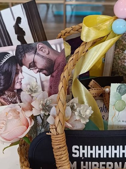 A close-up of the 'Mom To Be' hamper, showing the couple's photos and an advice card for parenthood.