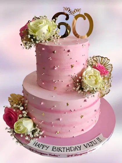 A beautiful two-tier pink cake for a 60th birthday. This design uses fresh flowers and a touch of gold leaf for a graceful and celebratory feel.