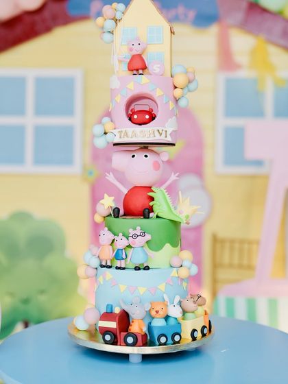 A magnificent, multi-tiered Peppa Pig cake, featuring the entire cast of characters and settings from the show.