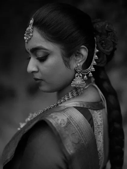 A classic black and white profile of a South Indian bride. The focus on her traditional jewelry, braided hair, and elegant posture highlights the timeless beauty of her bridal look.