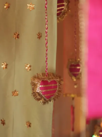 A close-up of the handcrafted details, including gota patti heart hangings and embroidered fabric drapes.