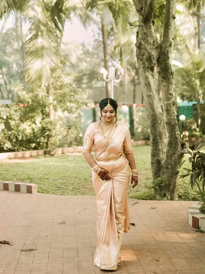 Walking with elegance. The simplicity of the makeup allows the rich texture of the Kanjeevaram saree and the heavy gold jewellery to take center stage.