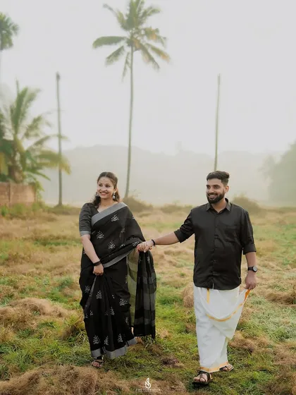Walking hand-in-hand through a misty field with coconut trees in the background, a classic South Indian landscape.