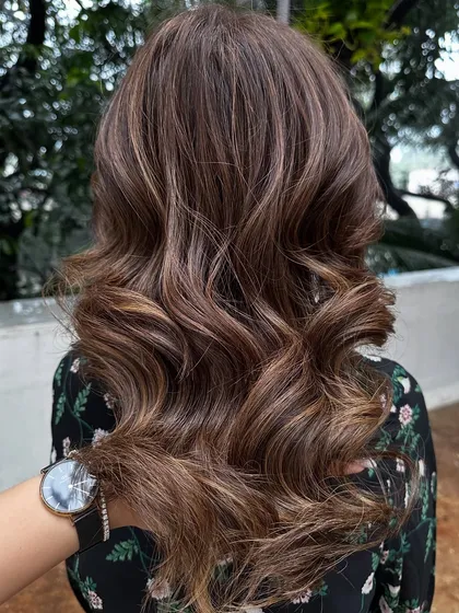 This client flew in from Dubai for my signature 'Caramello' color. I blended caramel highlights into her hair and covered her greys for a fresh, youthful look. The final style with soft waves really shows off the dimension.