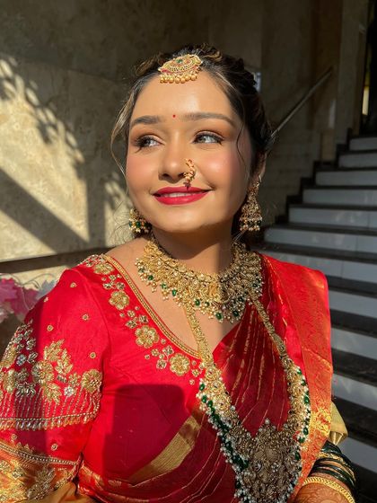 Golden hour glow for this Maharashtrian bride. The sindoori saree and statement nath are complemented by a dewy base and a bold red lip.