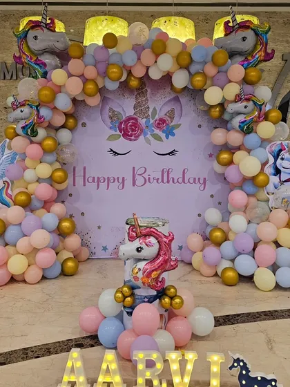 The complete Unicorn birthday setup, showcasing the main backdrop, personalized light-up name, and themed balloon decorations.