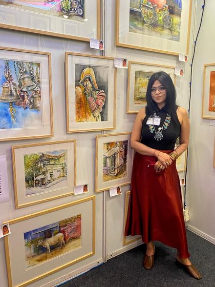 Me at my booth during the India Art Festival 2023. Standing next to my wall of art, feeling a mix of hurricane-level energy and immense gratitude.