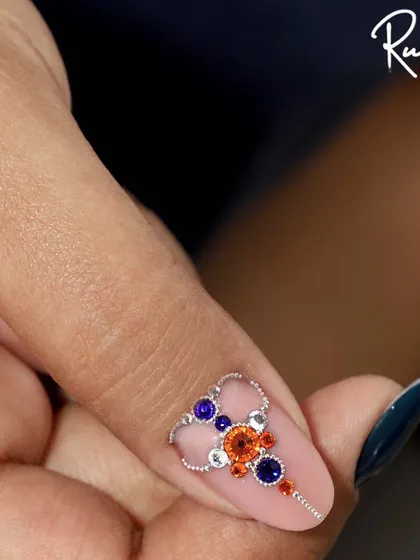 A stunning jewellery piece created with orange, blue, and silver crystals.