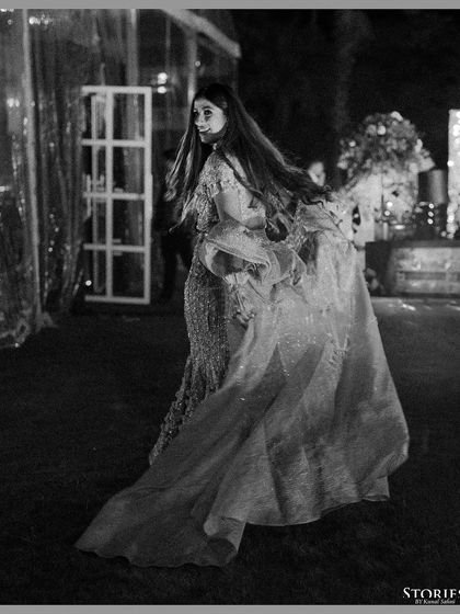A dynamic black and white shot of the bride, her cape flowing behind her as she walks, creating a sense of movement and drama.