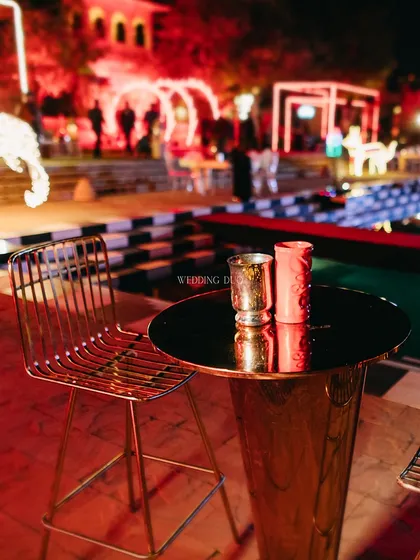 A sleek and modern bar setup for a cocktail night, with high-top tables and chairs set against a backdrop of neon lights and a checkerboard pool. This is where the magic of the night begins.