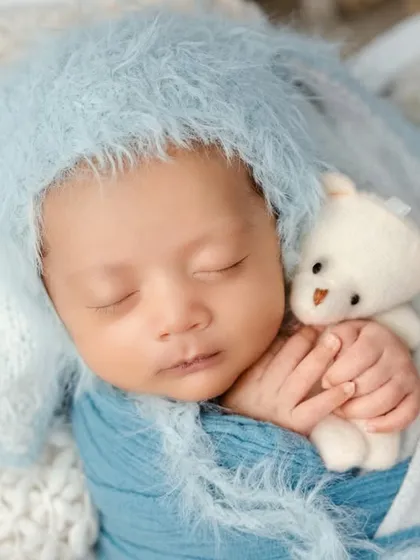 The peaceful, fleeting moments of a newborn are my specialty. I focus on safe and comfortable posing, using soft wraps and textures to create a serene portrait, like this little one dreaming sweetly with his tiny teddy bear.