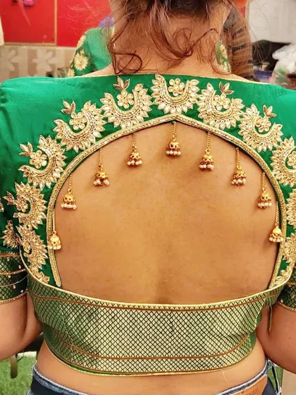 The beauty is in the details. This custom designer blouse features a dramatic arched keyhole back, framed with intricate gold zardosi embroidery and delicate hanging jhumkas. I work closely with clients to create unique back designs that make their ethnic wear truly one-of-a-kind.