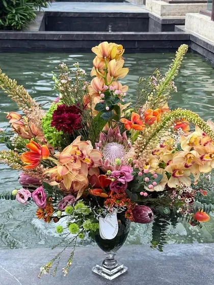 An arrangement that sings of saffron and tangerine. I brought together exotic protea, vibrant eremurus, and delicate orchids to create a piece full of texture and warm energy, perfect as a striking centerpiece for your home.