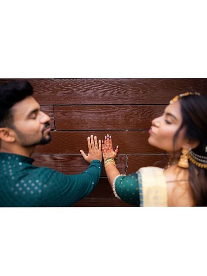 A playful and modern engagement portrait. The couple's hands meet on a textured wall, their expressions full of fun and affection.